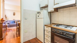 A compact kitchen with a refrigerator, stove, and wooden cabinets. - Indipendenza Retreats (Bologna)