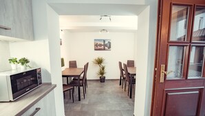 A modern kitchen with a microwave, cabinets, and a dining area with chairs and a table. - Auberge Leipzig (Leipzig)