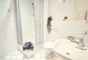 A modern bathroom with a glass-enclosed shower, a white sink, and a toilet. - Auberge Leipzig (Leipzig)