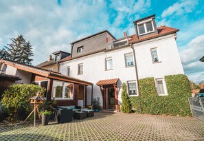 A two-story house with a tiled patio, a wooden swing set, and a small garden area. - Auberge Leipzig (Leipzig)