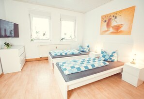A bedroom with two beds, a TV, a radiator, and a painting on the wall. - Auberge Leipzig (Leipzig)