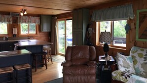 L’intérieur chaleureux d’un chalet comprend un coin cuisine, un fauteuil en cuir, un canapé et une table à manger.
