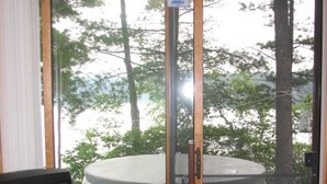 Une pièce dotée d’une porte-fenêtre coulissante donnant sur un espace extérieur avec un jacuzzi et un téléviseur placé dans un coin.