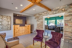 A lobby with a reception desk, two purple armchairs, a patterned rug, and a stone wall. - Leavenworth Village Inn (Leavenworth)
