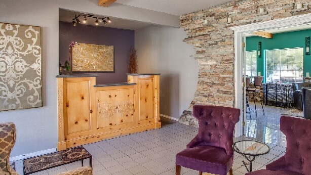 A reception area with a wooden desk, purple chairs, and a patterned rug. - Leavenworth Village Inn (Leavenworth)