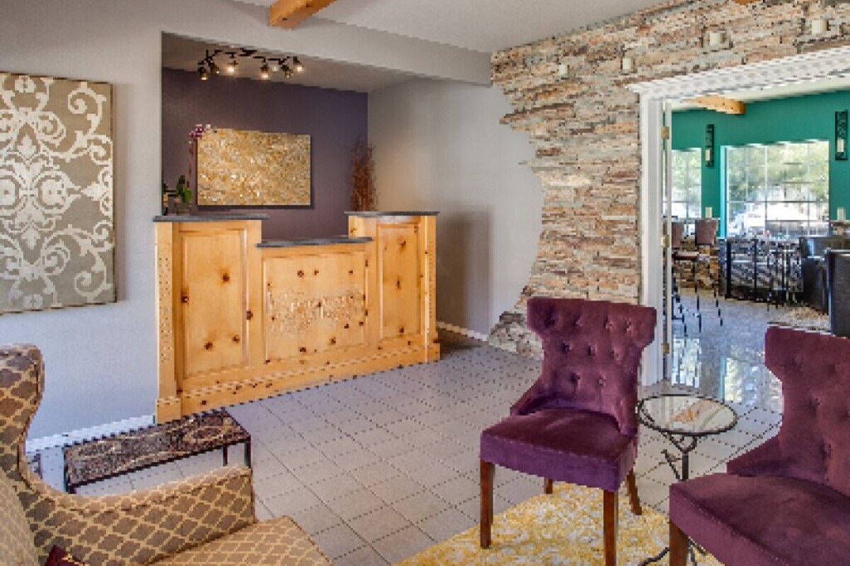 A reception area with a wooden desk, purple chairs, and a patterned rug.