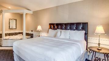 A large bed with a dark headboard, two bedside lamps, and a mirror on the wall.