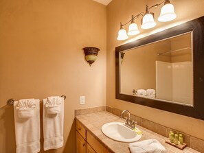 A bathroom with a large mirror, a sink, and two towel racks. - Leavenworth Village Inn (Leavenworth)