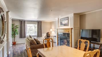 A cozy living room with a fireplace, a sofa, a dining table, and a TV.