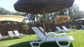 Patio con sillones blancos y un gran paraguas.