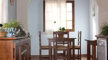 Un comedor con muebles de madera, una ventana con cortina y plantas en macetas.