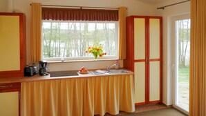 A kitchen with a window, a sink, and a table with a yellow tablecloth. - Ferienhäuser Seewiesen (Alt Schwerin)