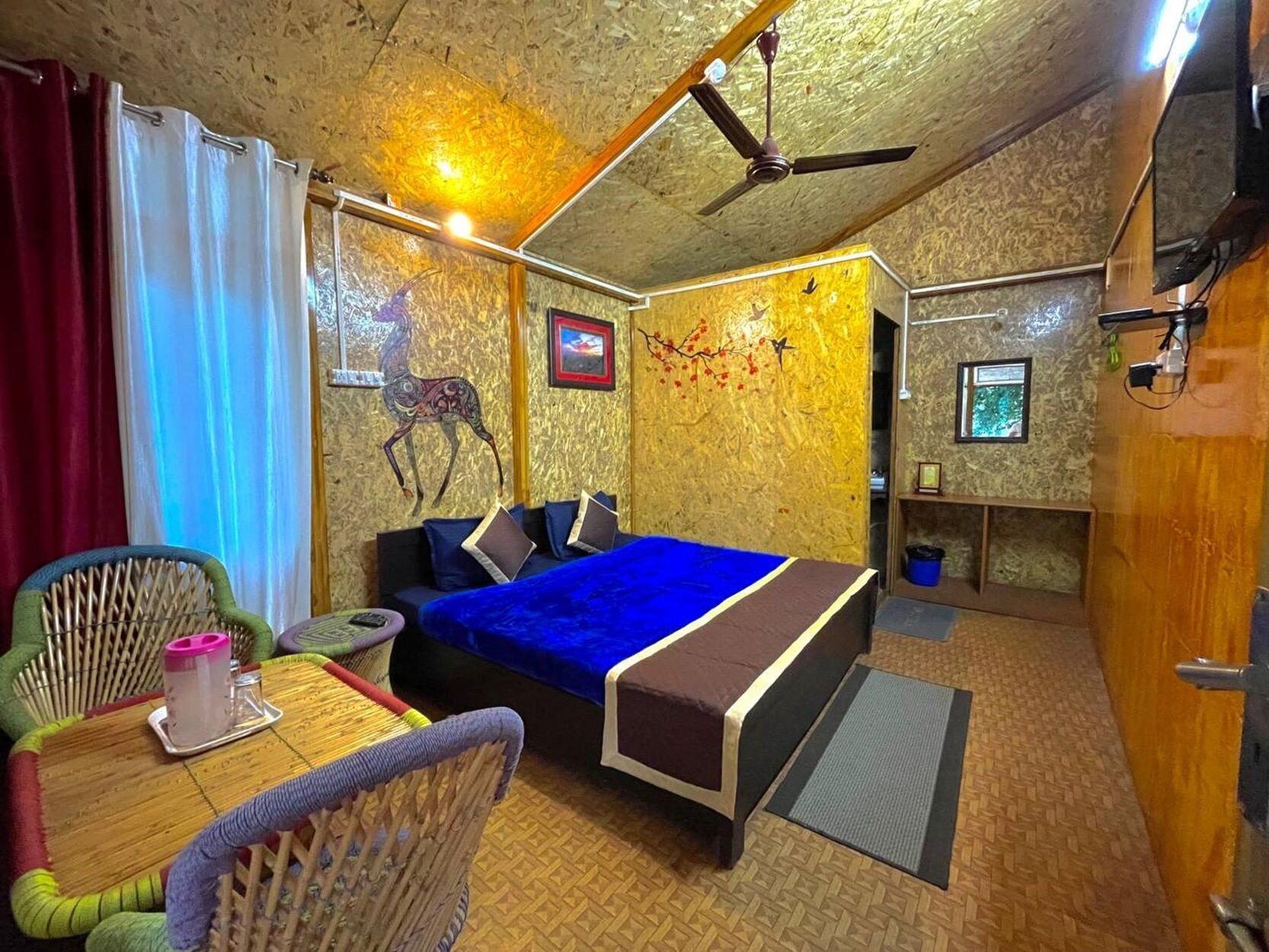 A room with a bed, a chair, a small table, and a ceiling fan.