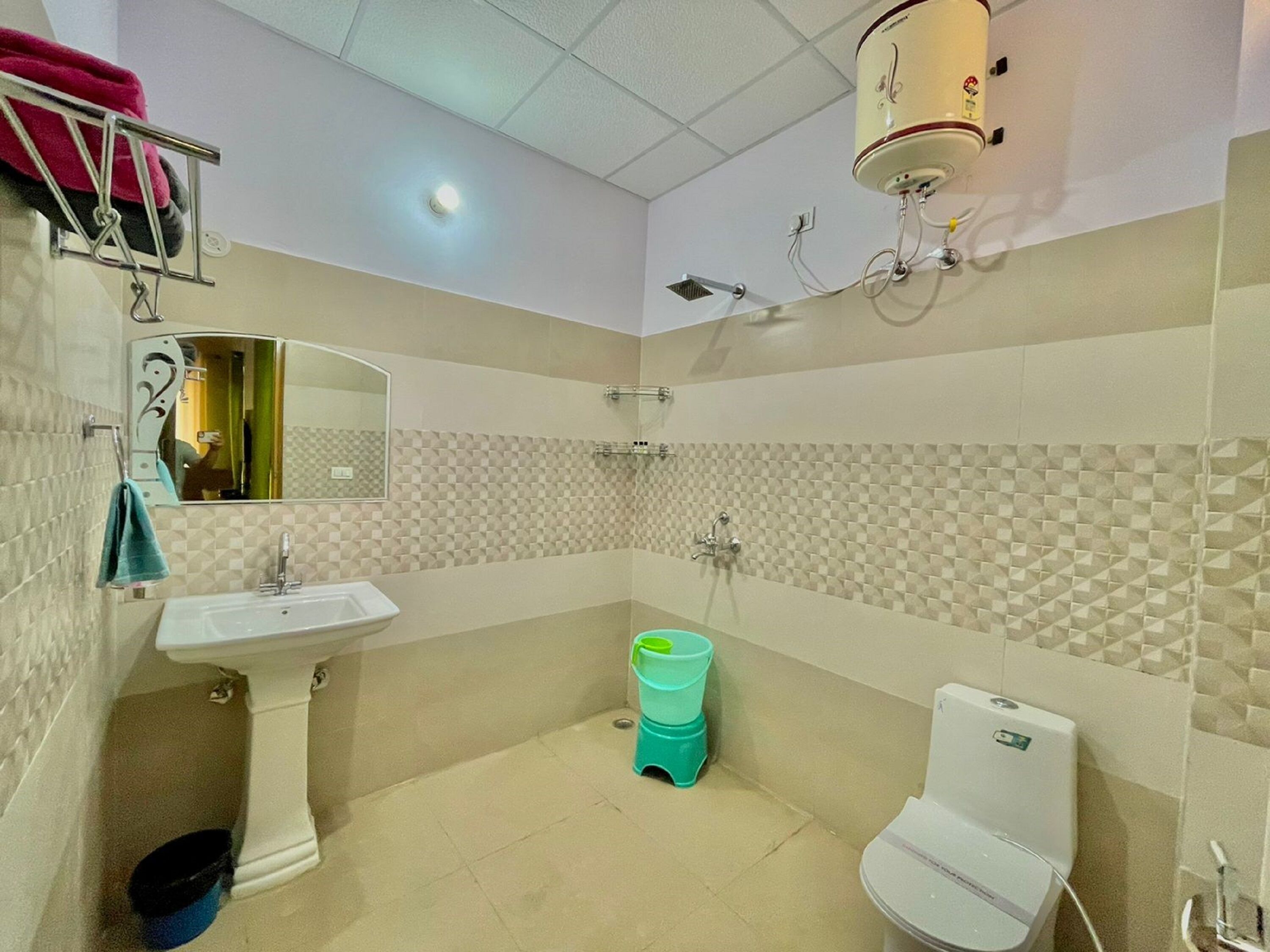 A bathroom with a pedestal sink, a toilet, a shower, and a mirror.