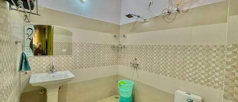 A bathroom with a pedestal sink, a toilet, a shower, and a mirror.