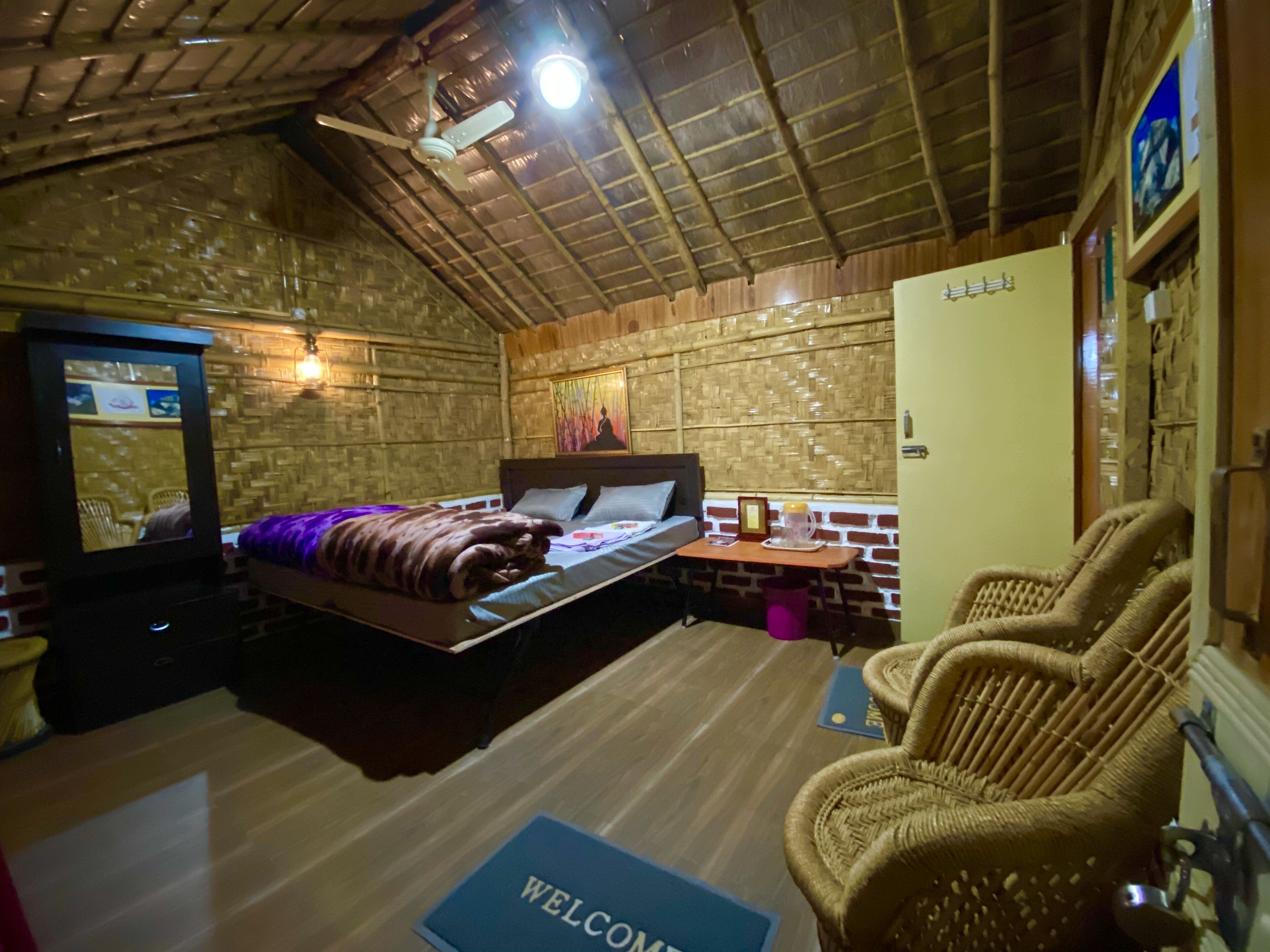 Een gezellige kamer met een bed, een televisie, een rieten stoel en een vloermat.