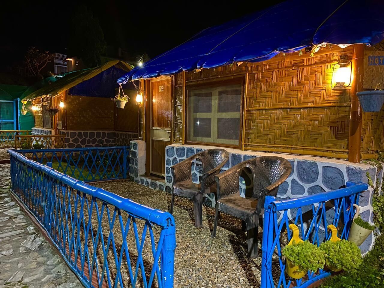 A rustic outdoor seating area with stone walls and a blue metal fence.
