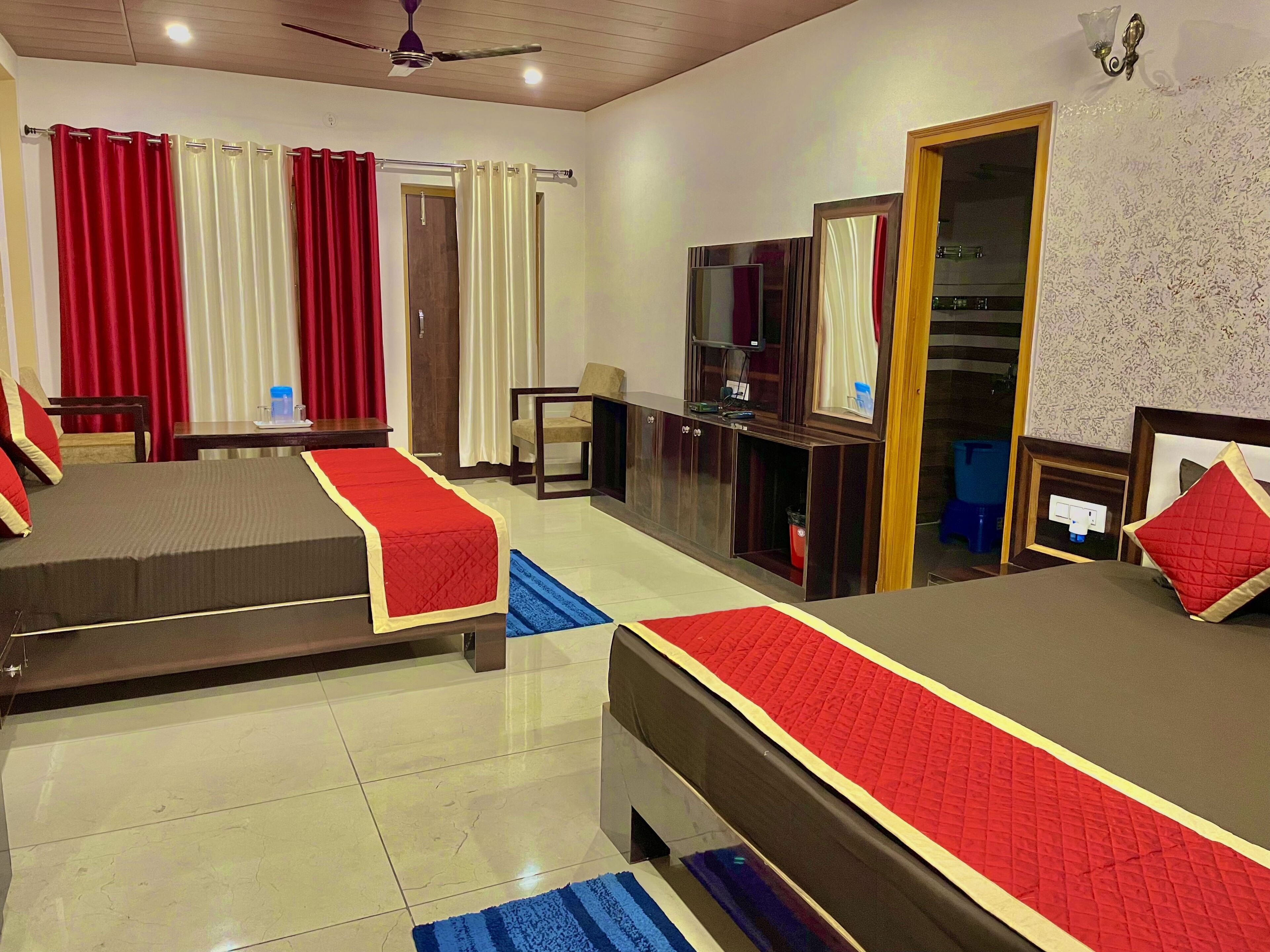 A hotel room with two beds, a desk, a TV, and a wardrobe.