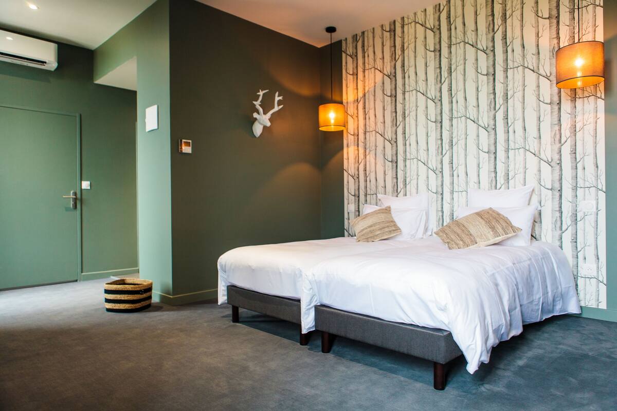 Une chambre à coucher moderne avec un grand lit, une décoration murale représentant une tête de cerf et un papier peint à motifs.