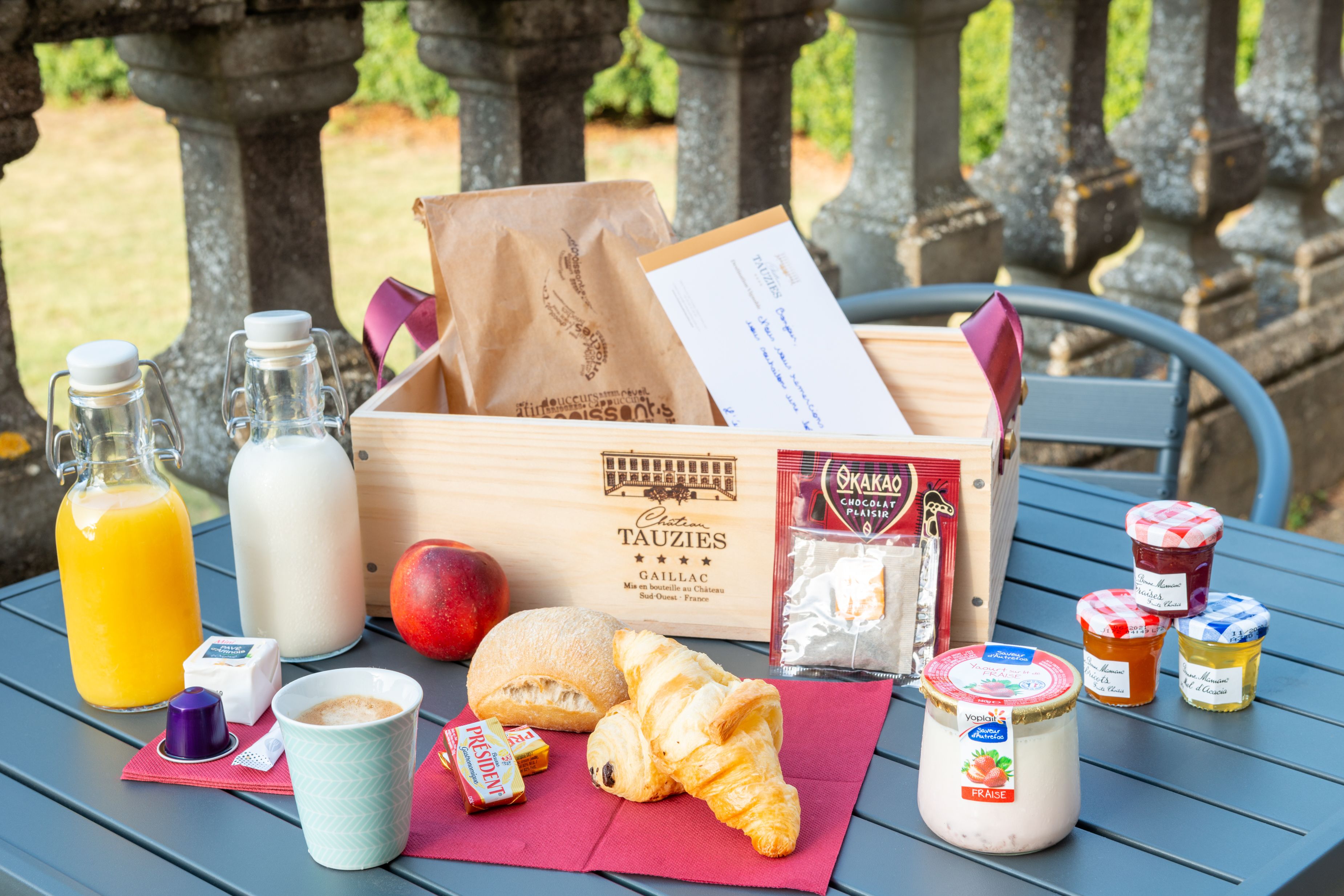Una mesa con comida para un picnic, como cruasanes, queso y fruta.