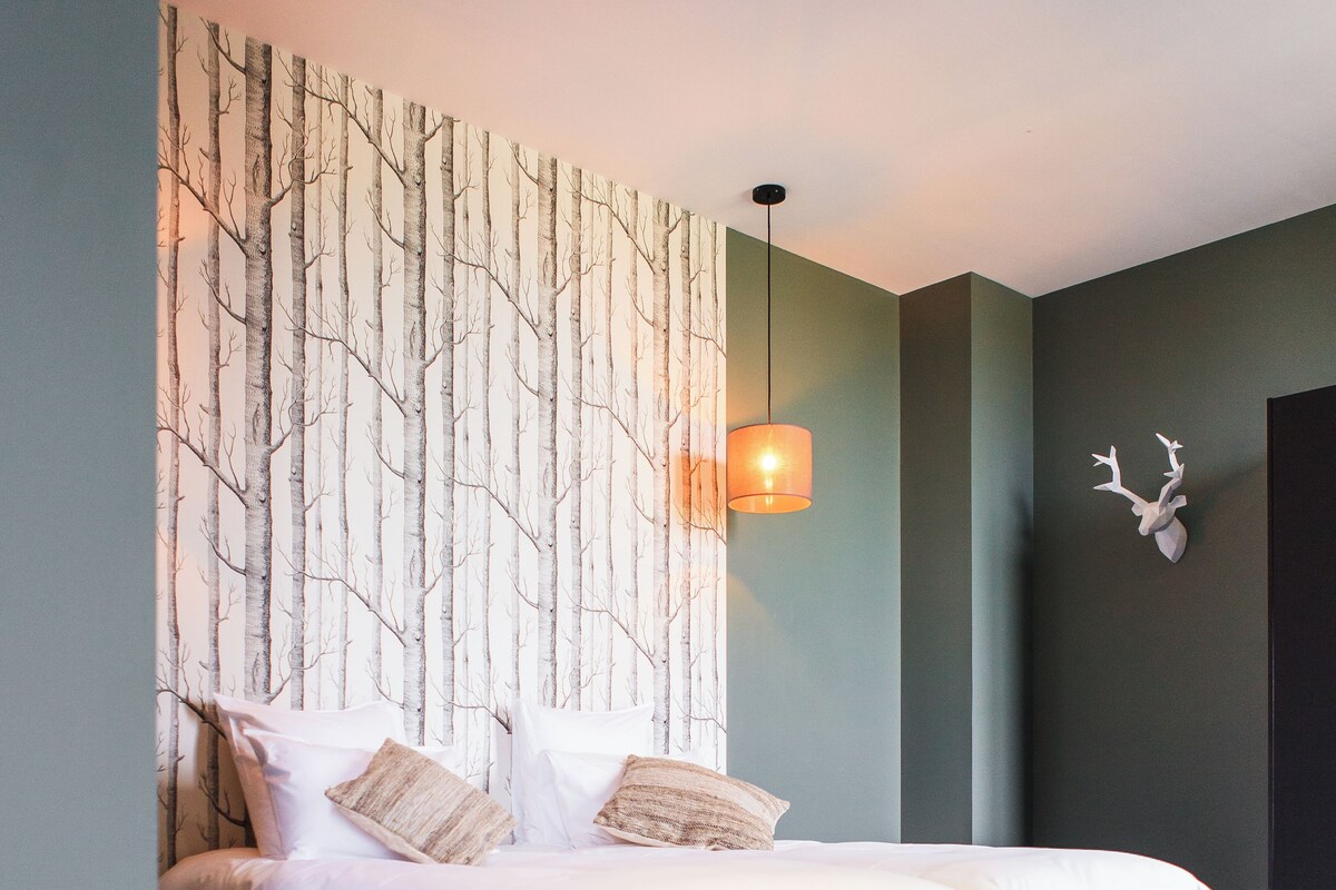 Een slaapkamer met twee bedden, een wandlamp en een decoratief object aan de muur.