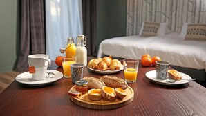Een ontbijttafel met croissants, toast, sinaasappelsap en een koffiekop.