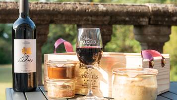 Una botella de vino, una copa de vino y dos frascos de comida sobre una mesa al aire libre.