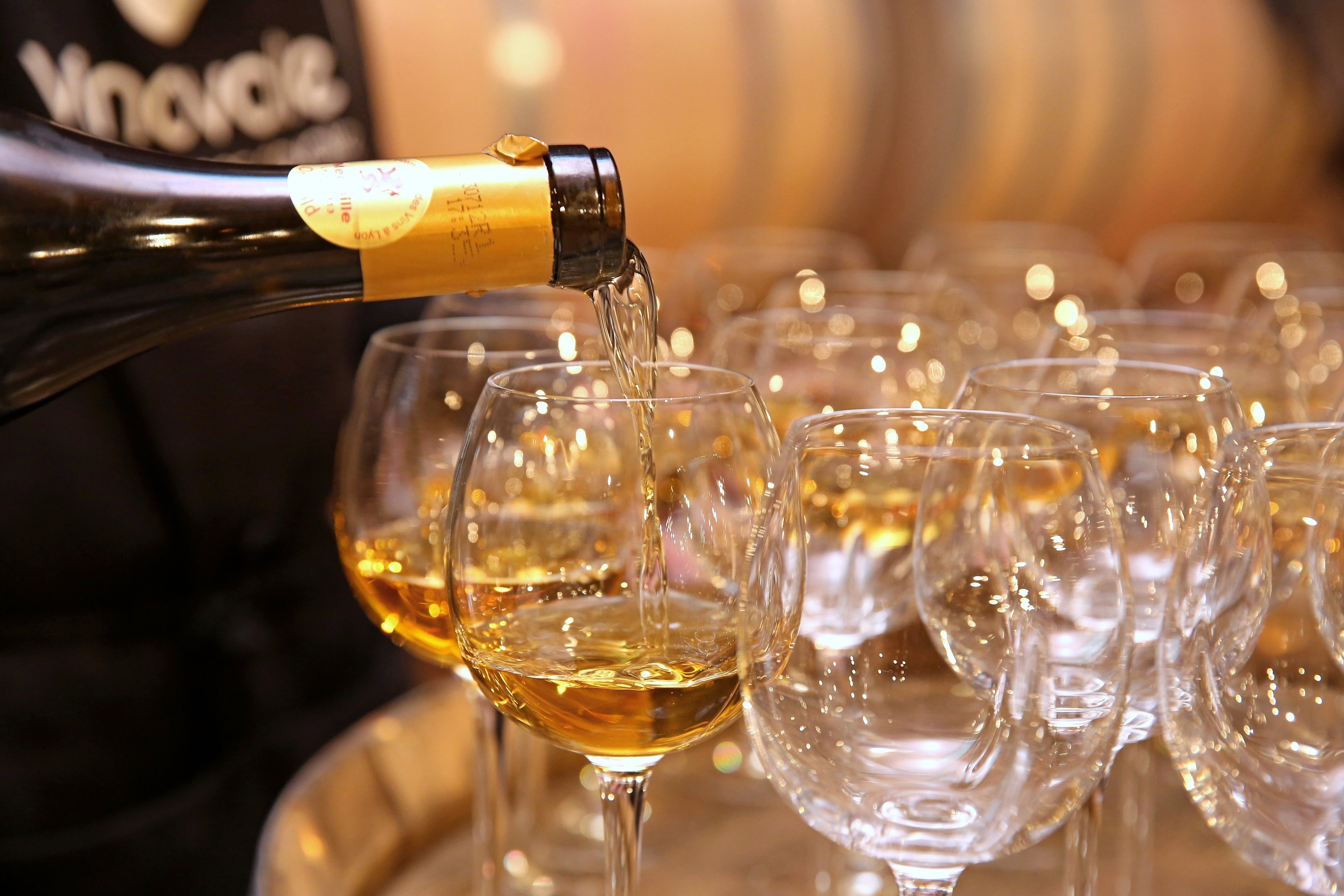A bottle of wine being poured into glasses.