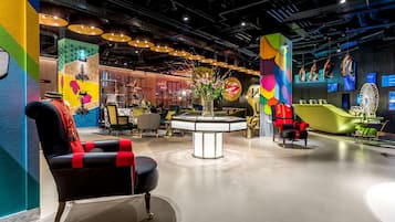 A modern interior with a black leather chair, a central table with a vase, and colorful walls.