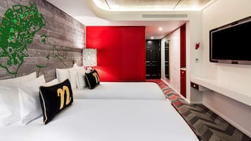 Una habitación de hotel con una cama grande, un televisor montado en la pared y una pared de acento roja.