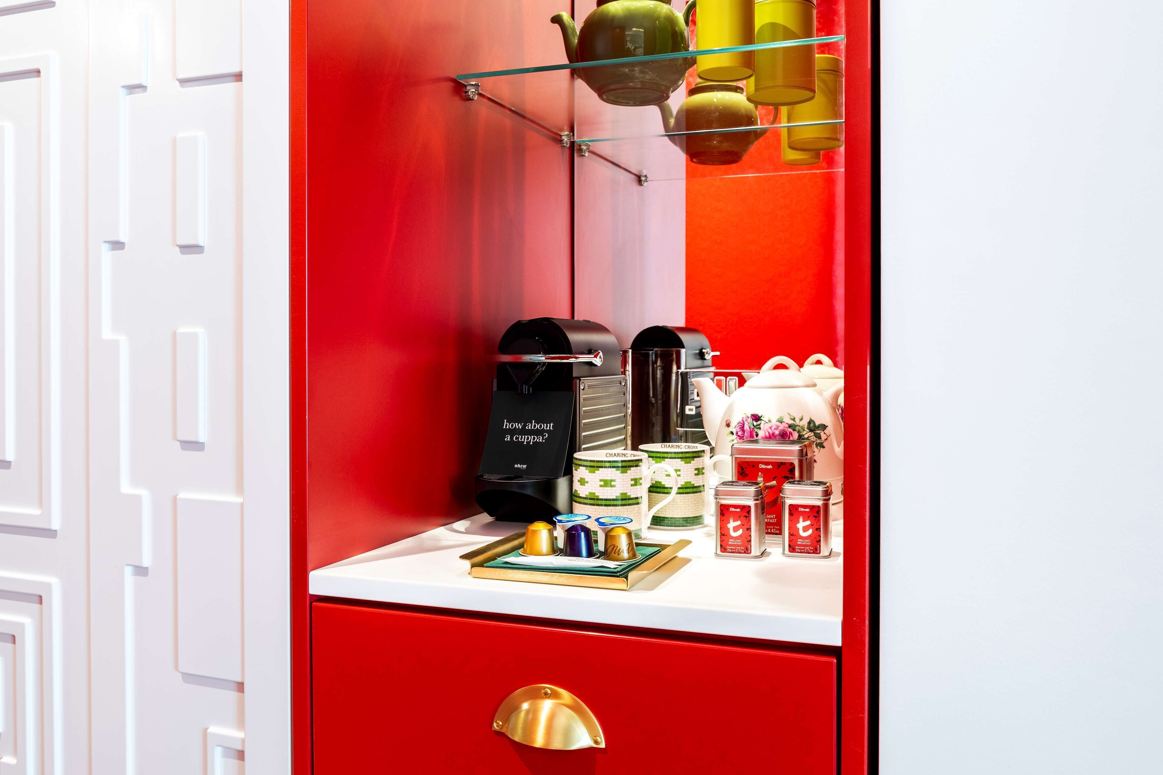 Una habitación en tonos rojo y blanco con una cafetera, tazas y un juego de té sobre la encimera.