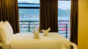 A hotel room with a bed, two towels arranged in swan shapes, and a view of a lake and buildings. - Treasure Island Hotel (Masbate City)