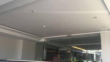 A modern hotel interior with a glass staircase, a reception desk, and a view of the lobby area.