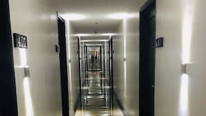 A long, narrow hallway with reflective flooring and walls, leading to multiple doors marked with numbers. - Treasure Island Hotel (Masbate City)