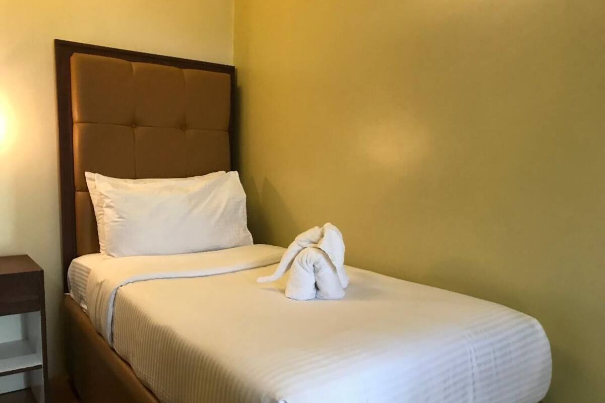 A neatly made bed with white linens and a folded towel on the bed.