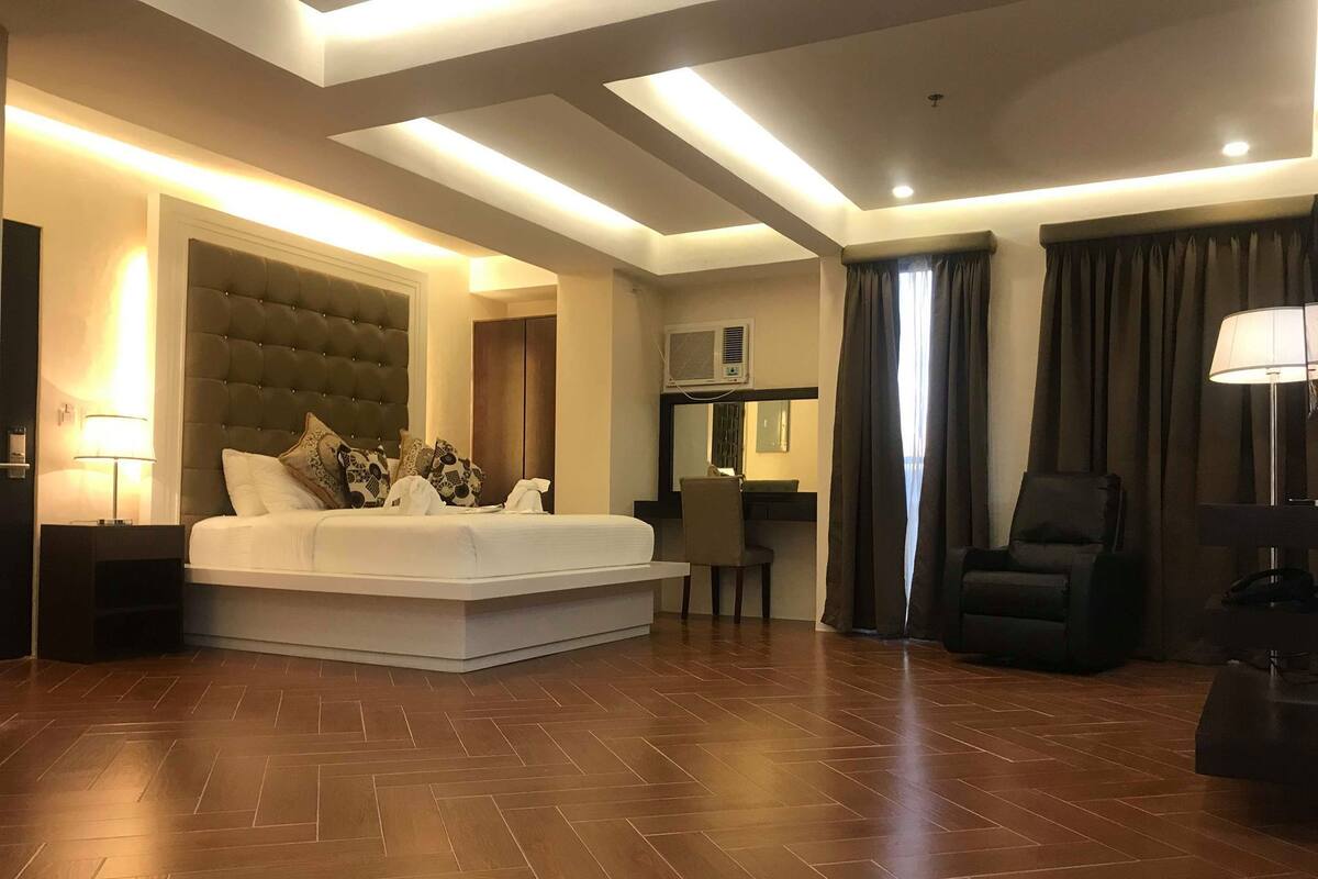 A modern hotel room with a large bed, a desk, and a chair.