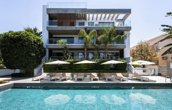 Um hotel moderno com piscina, espreguiçadeiras e guarda-sóis.
