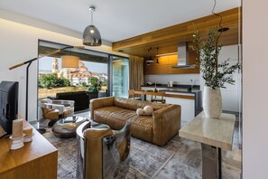 Uma sala de estar moderna com um sofá de couro, uma mesa de centro e vista para a cidade.