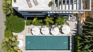 An aerial view of a modern hotel with a swimming pool, sun loungers, and a covered seating area. - Sofia Luxury Residence (Paphos)