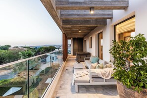 Uma varanda com um sofá, uma mesa de centro e um vaso de planta.