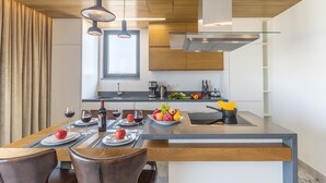 A modern kitchen with a central island, wooden ceiling, and pendant lighting. - Sofia Luxury Residence (Paphos)