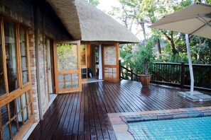 A wooden deck with a pool, a thatched roof structure, and a view of the surrounding greenery. - Kruger Park Lodge Unit 252 (Mbombela)