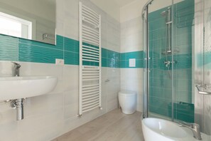 Een moderne badkamer met een wit wastafel, een douche met glazen wanden en een toilet.