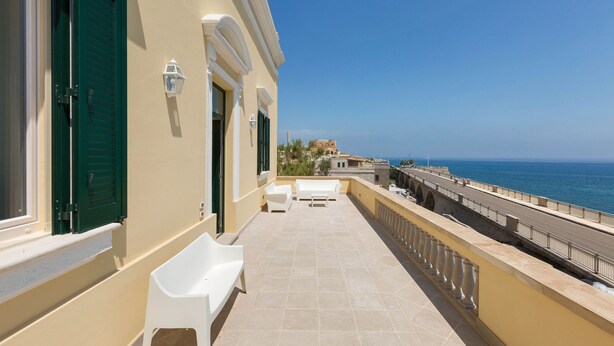 A balcony with a view of the sea, featuring a railing, a bench, and a table. - Villa Dorella (Castrignano del Capo)