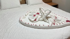 A neatly made bed with a decorative towel arrangement in the center.