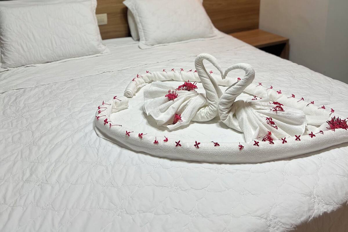Un lit bien fait, agrémenté d’une serviette décorative placée au centre.