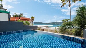 A swimming pool with a tiled floor, surrounded by greenery and a view of the sea. - Atika Villa 1 oceanfront pool villa (Patong)