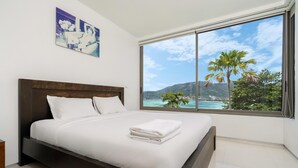 A bedroom with a large window, a bed, and artwork on the wall. - Atika Villa 1 oceanfront pool villa (Patong)