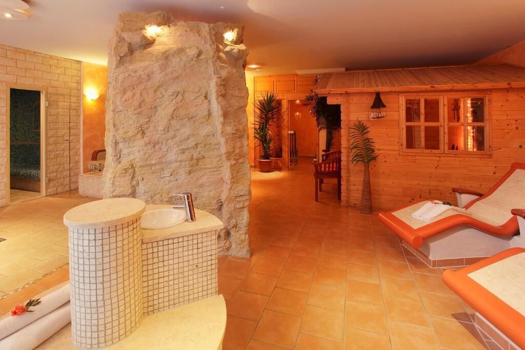 A spa area with a stone wall, two sinks, and a wooden cabin-style room with a window.