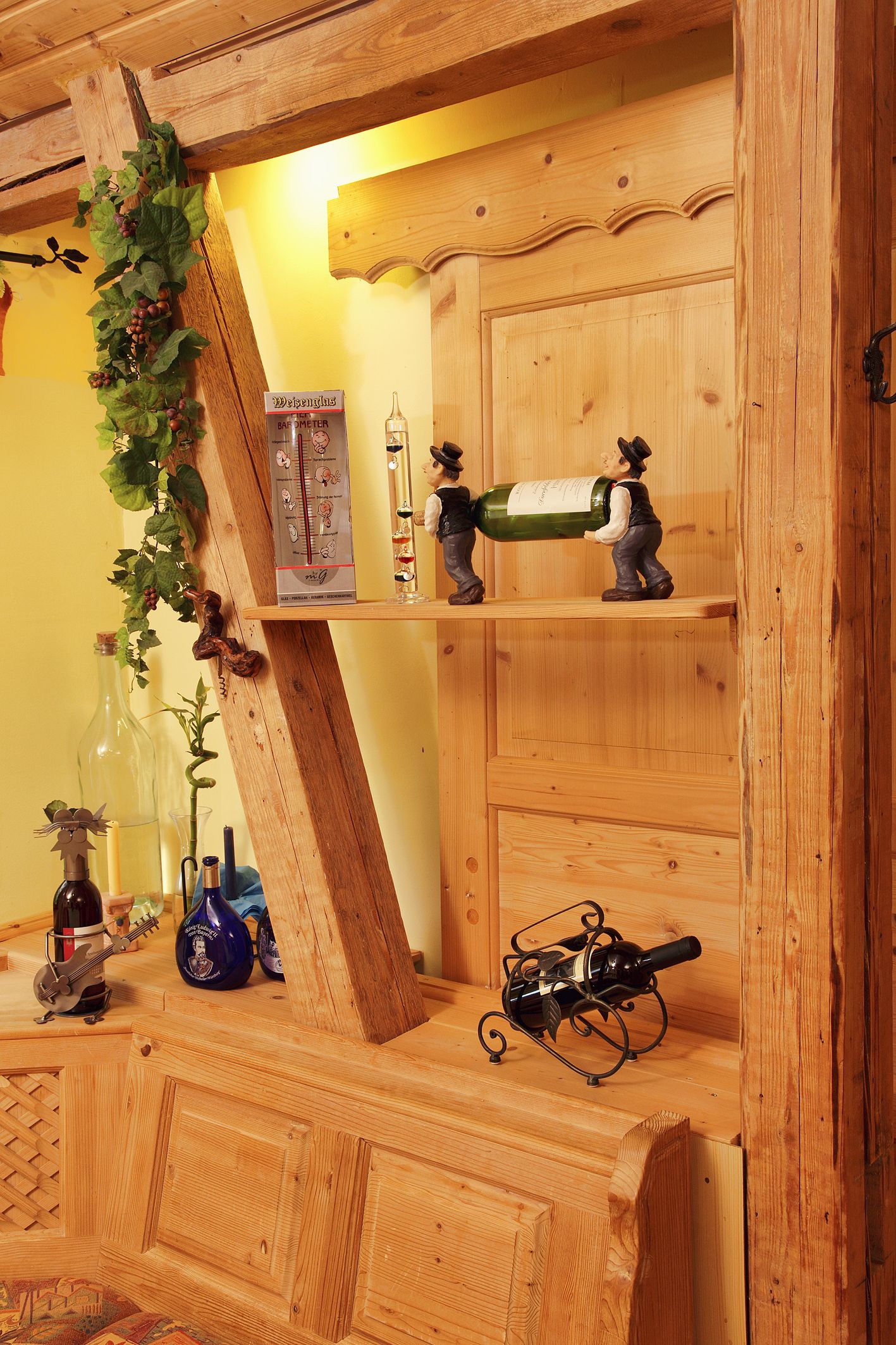 A wooden wine rack with bottles and a decorative figure.